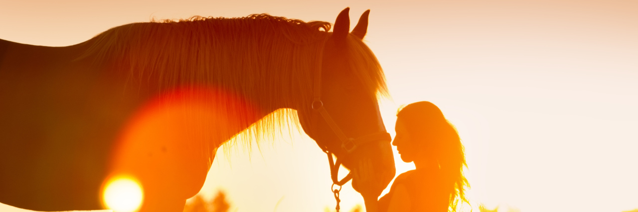 Beautiful silhouette of woman and horse at sunset.