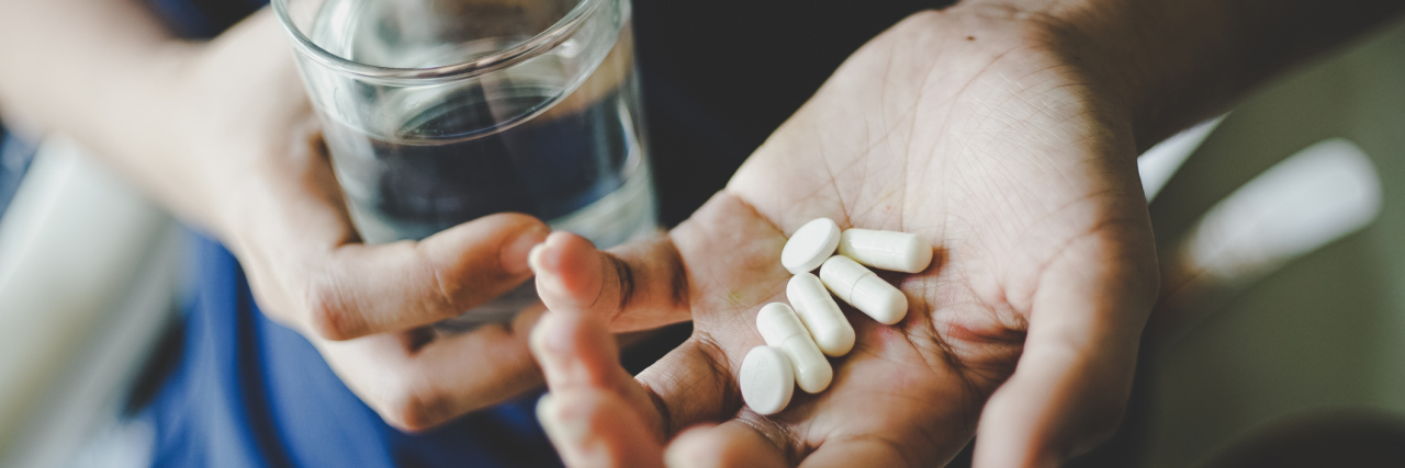 When I'm Shamed Into Thinking I Don't Need My Pain Medication woman holding pills in hand and glass of water