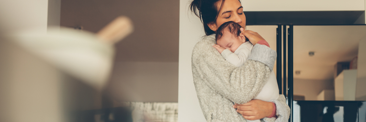 A mom holding her newborn baby in a kitchen.