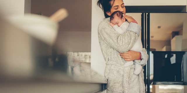 A mom holding her newborn baby in a kitchen.