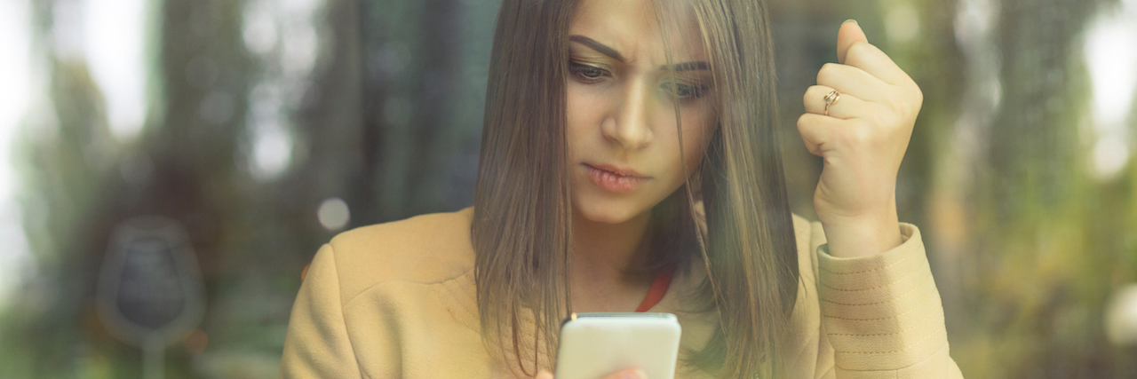 Assumptions People Made After Kate Spade's Suicide A woman holding her phone, clenching her fist