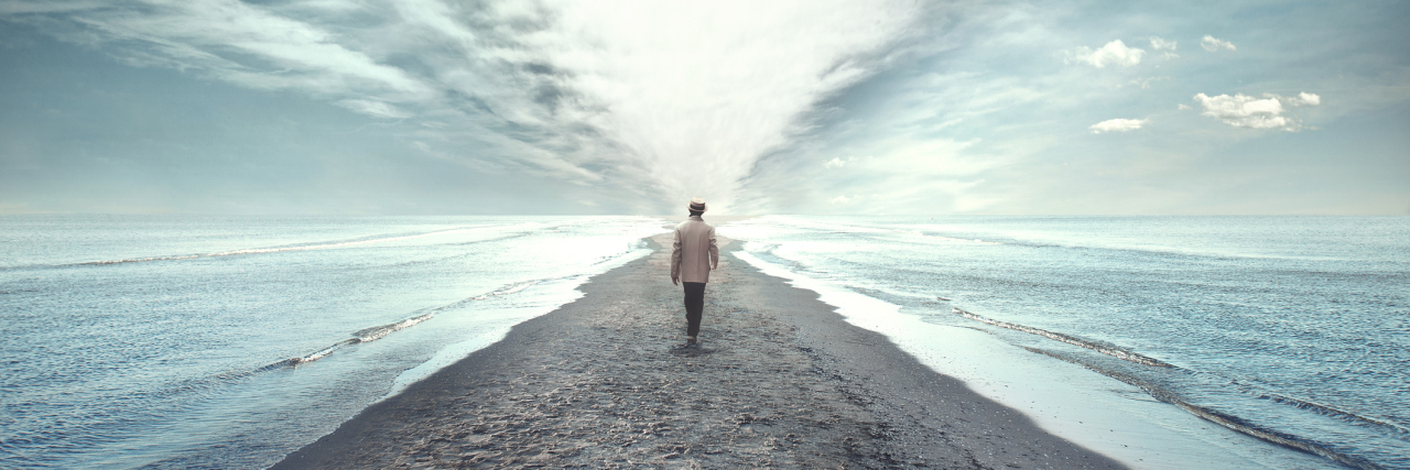 A man walking on a pathway between two seas.
