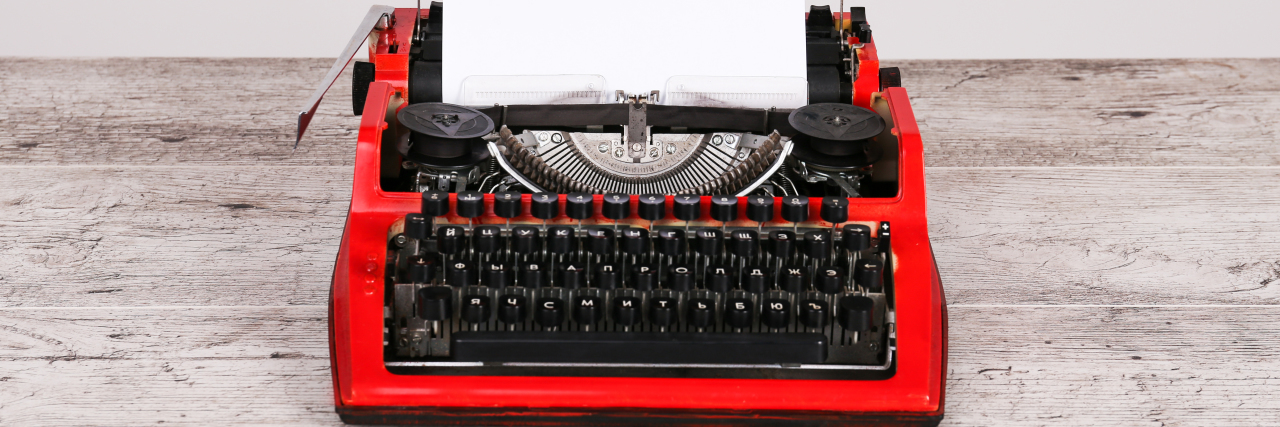 Vintage red typewriter on rustic table.