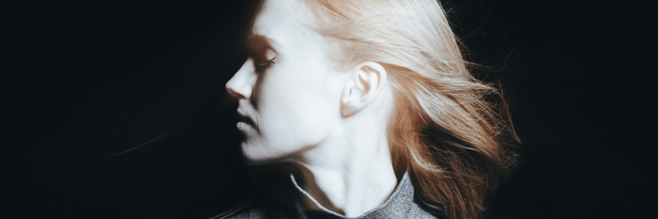 Why My Multiple Sclerosis Doesn't Define Me woman facing away with bright light shining on her against dark background