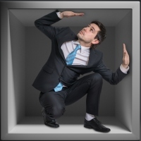 Businessman trapped inside uncomfortable small box.