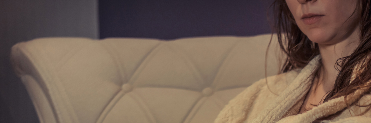 woman sitting on the couch in a bathrobe holding a cup of tea