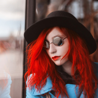 A woman with red hair look out a window.
