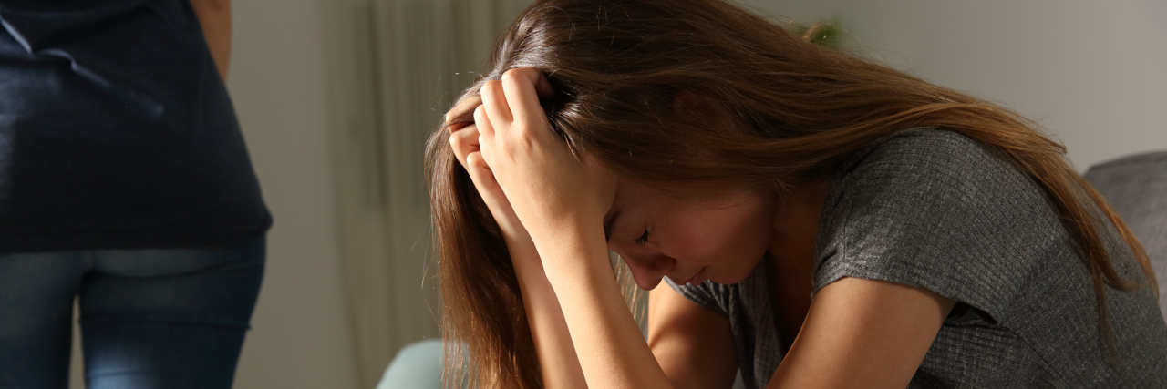 10 Things Family Members Should Never Say to Lyme Patients A person walking away from an upset woman, sitting on a couch.