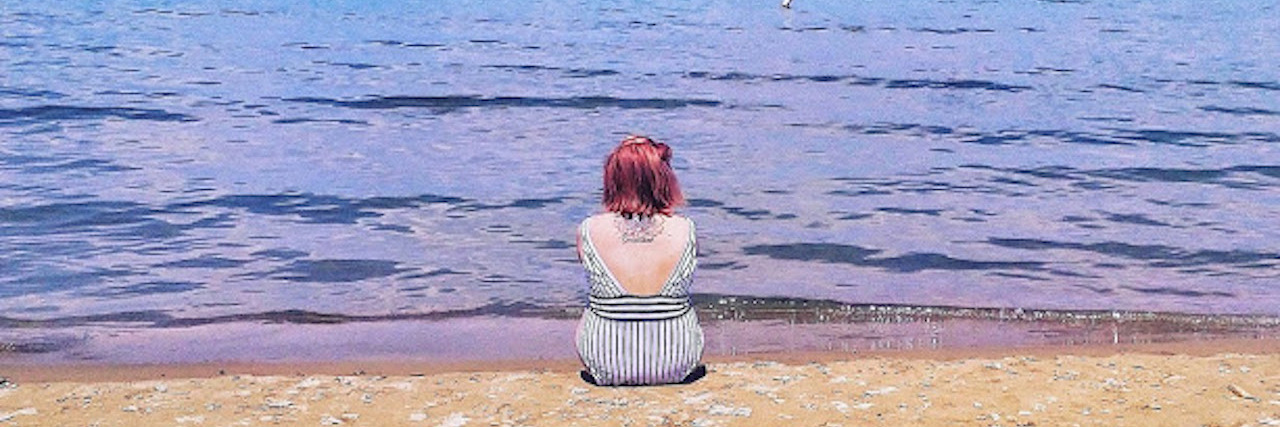 A picture of the writer sitting in front of a body of water.