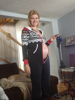 Picture of woman showing her pregnant belly wearing a sweater buttoned just below her breasts to show her stomach