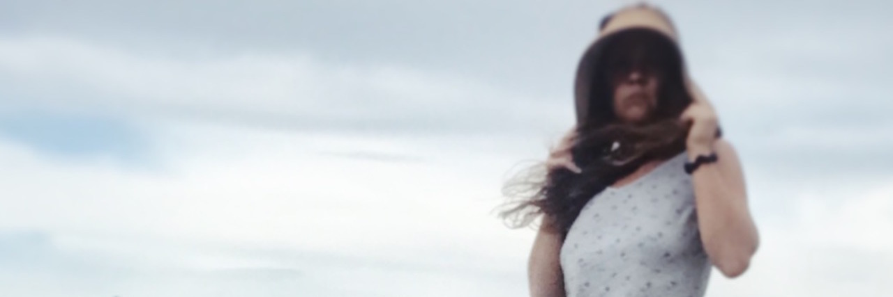 When Your Illness Makes You Run on Auto Pilot A picture of the writer standing outside in a sun dress and boots.