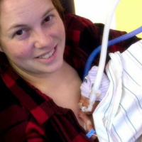 Mother holding preemie baby at hospital. Baby is so small laying on mom's chest