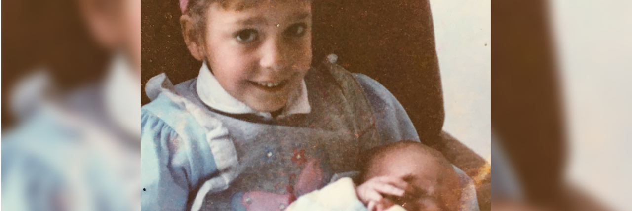 What It Was Like Raising Two Kids While Living With Crohn's Disease old photo of little girl holding a baby