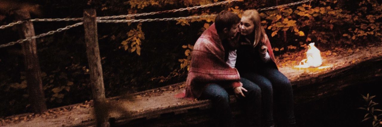 How to Tell Your Significant Other About Your Mental Illness couple sitting on bridge in wildness with fire beside them