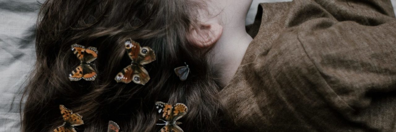 The Butterfly Project and the Crisis Text Line Helped Me Not Self-Harm woman lying on bed with butterflies in her hair