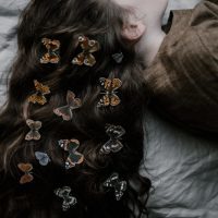 woman lying on bed with butterflies in her hair