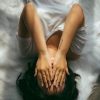 woman lying on bed with hands covering face
