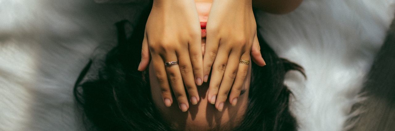 Panic Attacks: What They Are and How I Cope With Them woman lying on bed with hands covering face