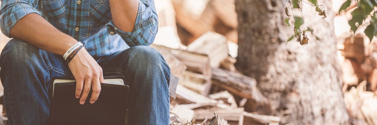 How God Works Through My Bipolar Disorder contemplative man sitting by tree holding bible