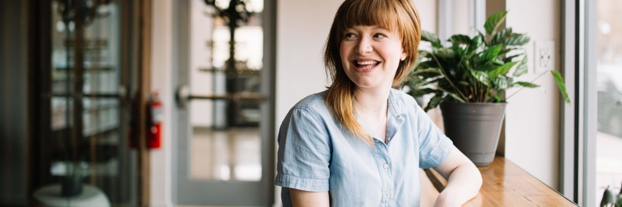 young woman sat at desk looking over her shoulder and laughing