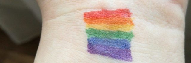 person's wrist with pride flag coloured on it