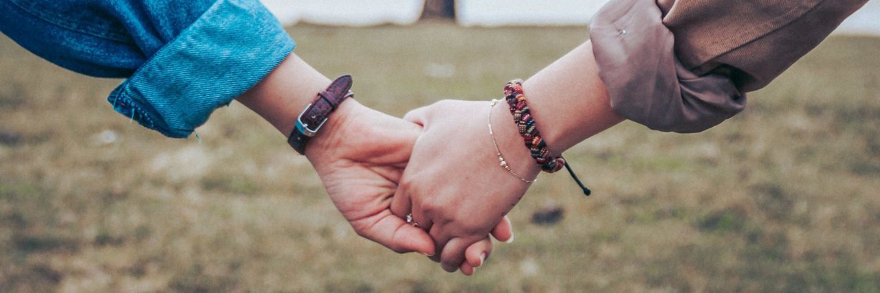 How to Best Support Someone With Bipolar Disorder two people holding hands in front of large tree