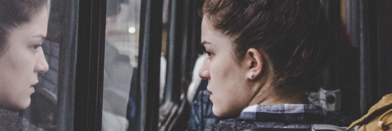 woman on bus looking worried and looking out window
