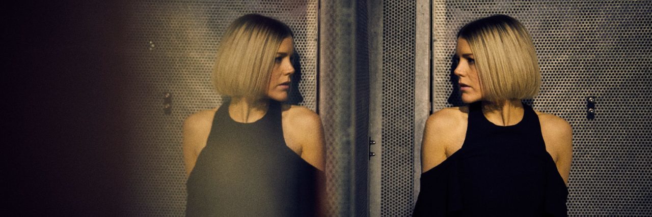 Coming to Terms With 'High-Functioning' Anxiety When It Doesn’t Stop blonde woman looking at her reflection in mirror