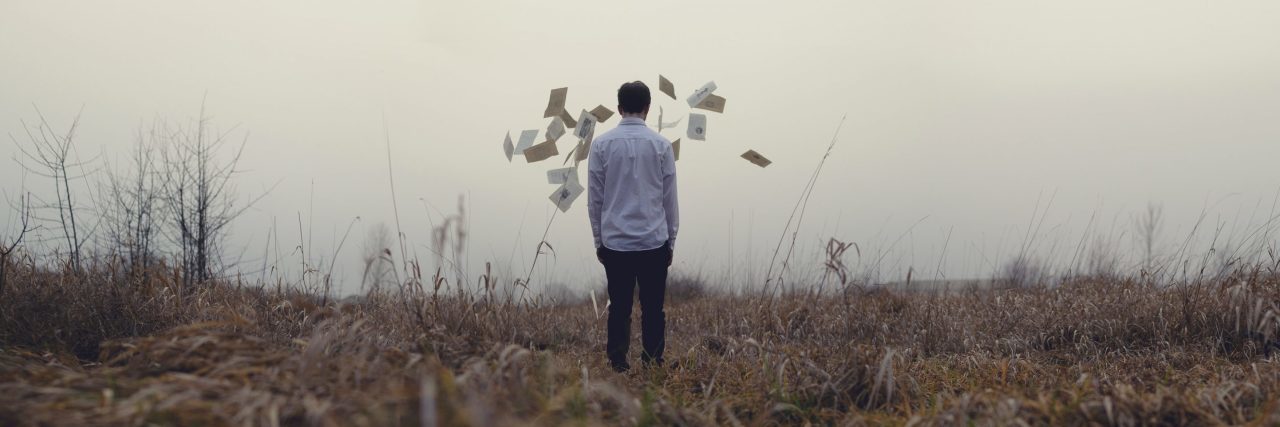 How Self-Help Books Are Actually Harming Men and Society man facing away from camera in field having thrown pages into air
