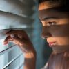woman peeking through the blinds