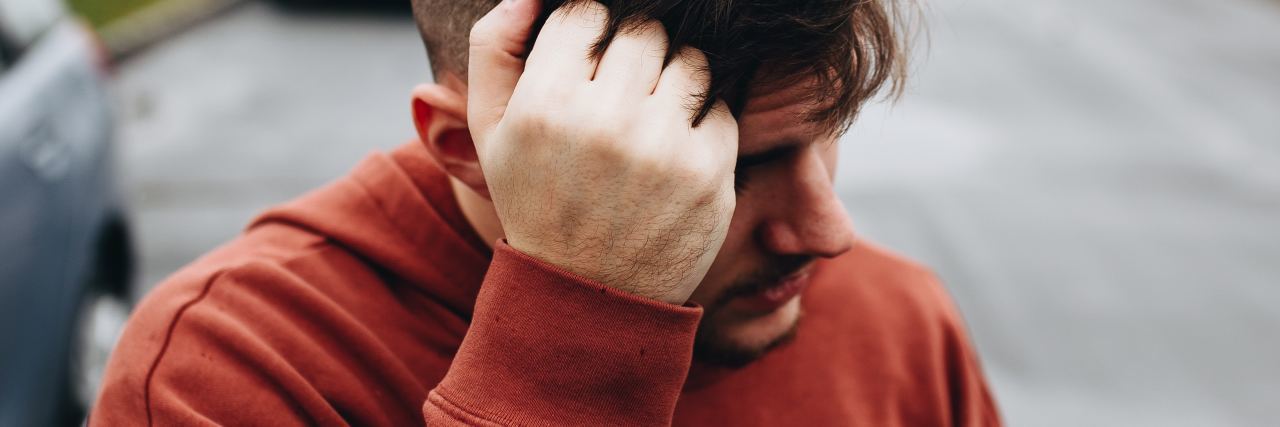 Uncovering Childhood Trauma and I Likely Have PTSD photo of man with hand raised to head in thinking expression and looking away from camera