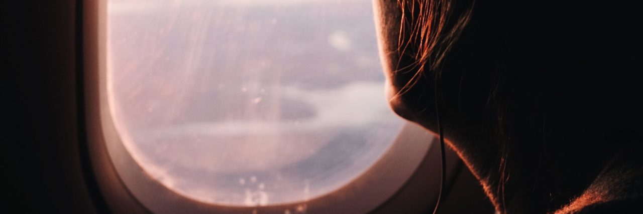 young woman looking out of plane window
