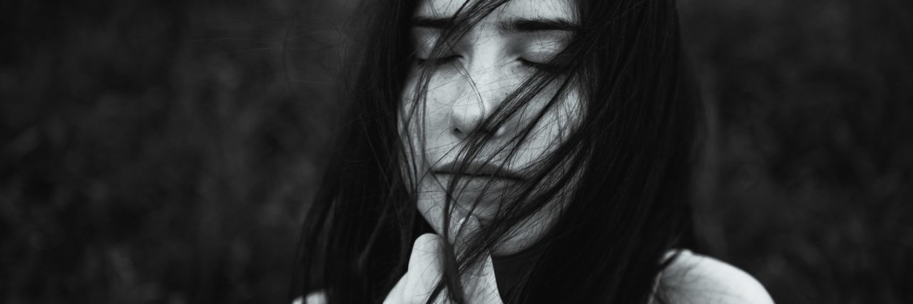 black and white photo of young woman holding hair and eyes closed