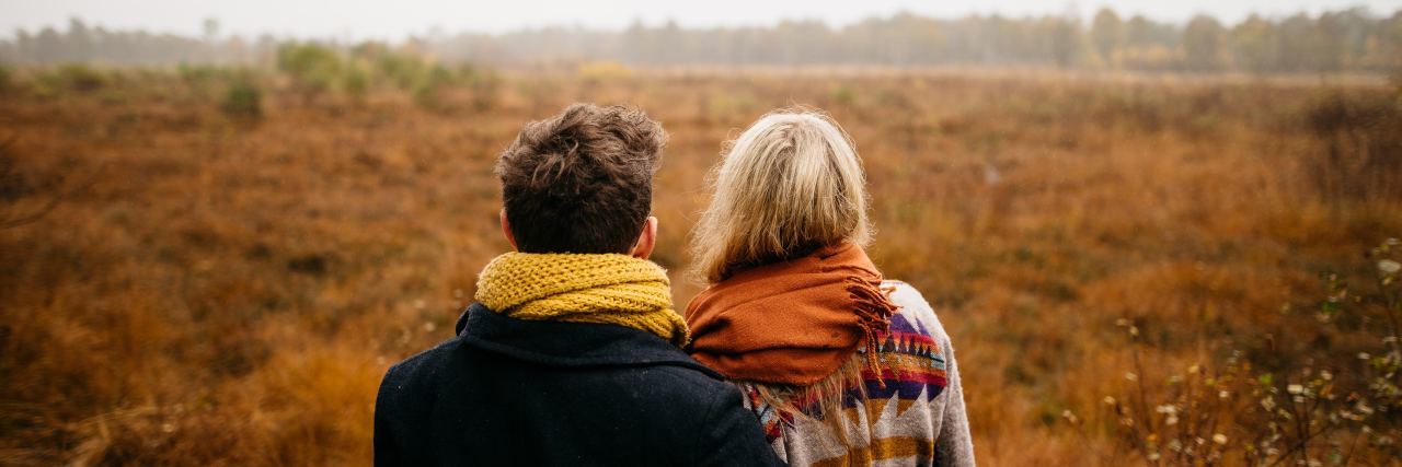 Couple standing in autumn field.
