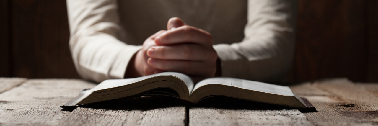 How You Should (and Shouldn't) Pray for Me and My Illness woman praying over a bible on a wooden table