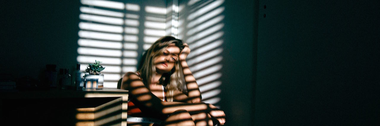 Should I Be Committed to a Psychiatric Hospital' A woman sitting in the corner of her bedroom