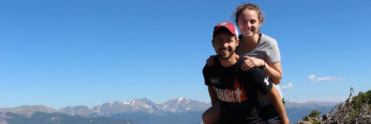 woman piggyback on man at top of mountain