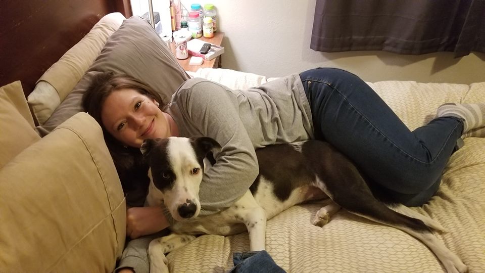 woman lying in bed hugging her dog