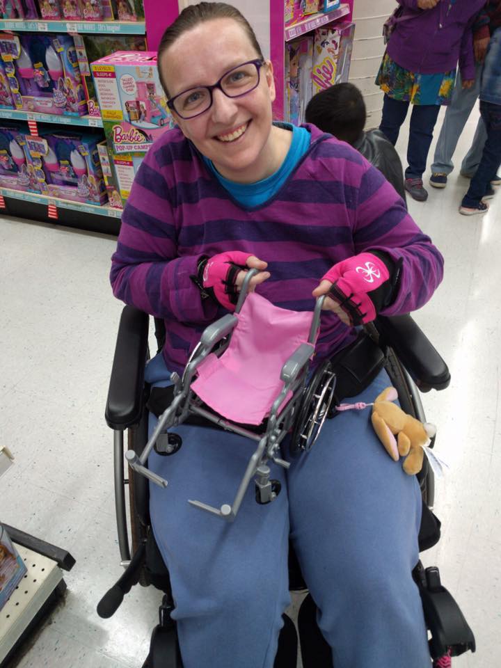 woman out shopping in her wheelchair holding a tiny toy wheelchair