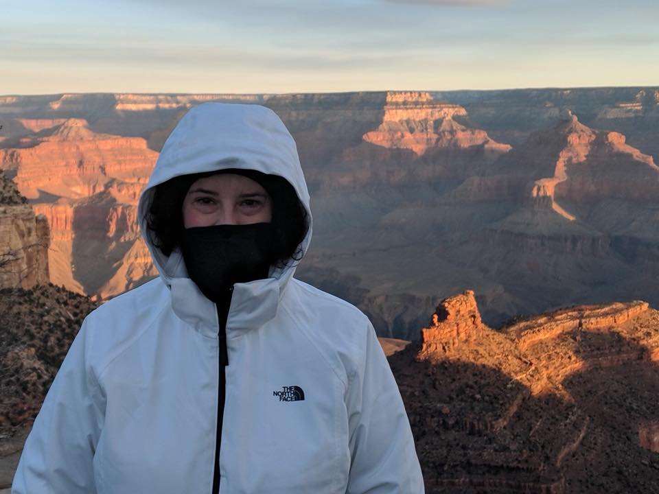 woman wearing a white jacket and posing in front of the grand canyon