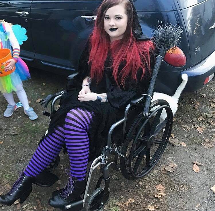woman dressed as witch using wheelchair decorated with broom