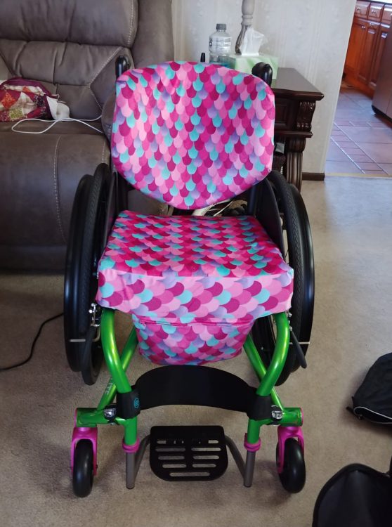 wheelchair with pink and blue seat cover and pocket in front