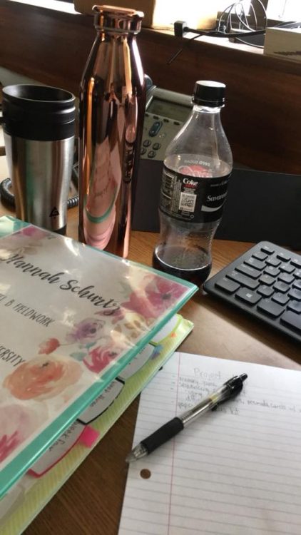 desk with binder, pen, paper, bottle of coke and keyboard