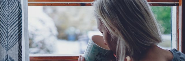 A woman drinking a cup of tea and looking out a window. Text reads: 57 Self-Care Ideas for a Bad Mental Health Day