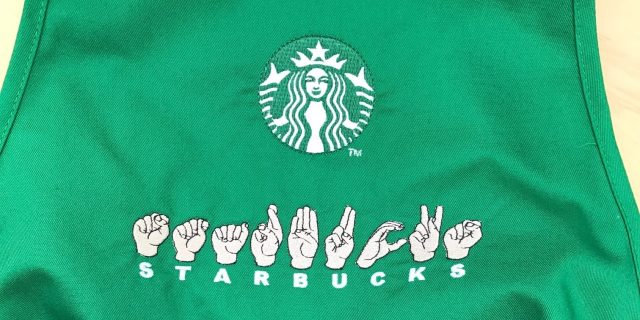 Starbucks to Open Its First Sign Language-Based Coffeeshop in the U.S. Starbucks apron with the word "Starbucks" in fingerspelling.
