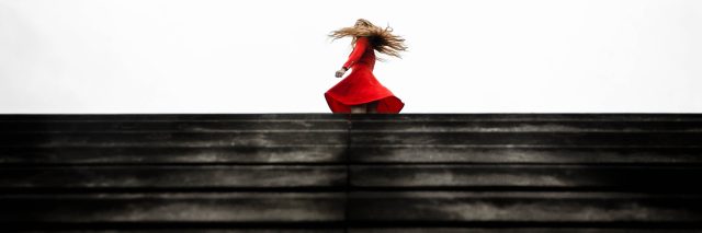 woman spinning on top of steps wearing red dress