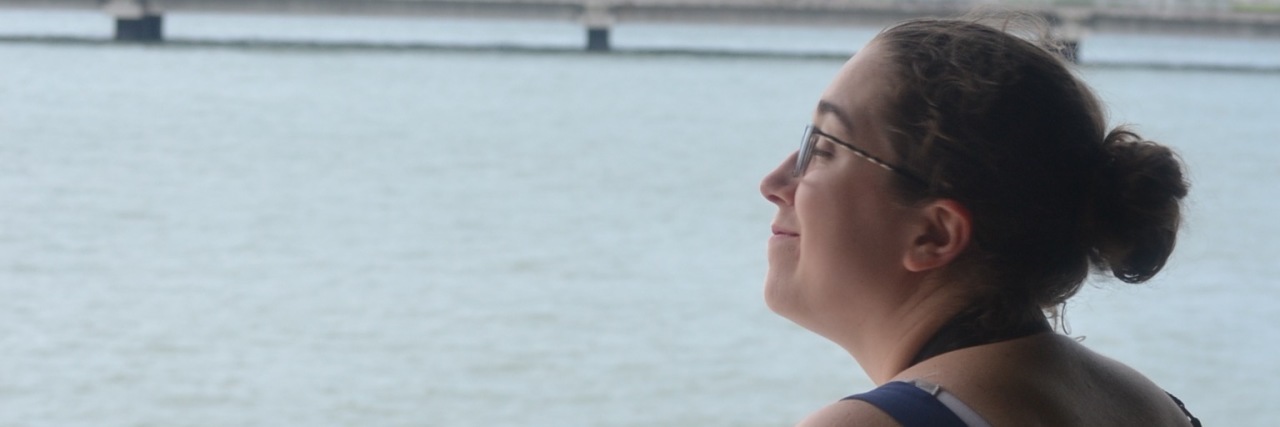 How I'm Growing My Wings Back After Traveling Overseas With an Illness A picture of the writer looking at a body of water.