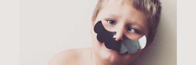 Boy wearing a fake mustache and holding his guinea pig