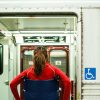 Young woman in a wheelchair entering a subway train.