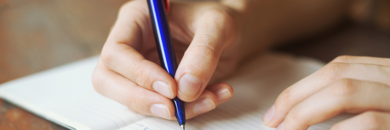 a person's hands writing in a diary